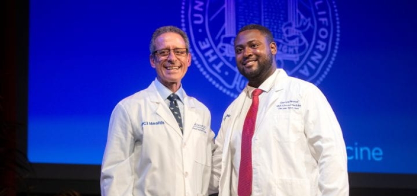 A photo of Darrys Reese receives his first physician’s white coat and a welcome from Dr. Michael J. Stamos