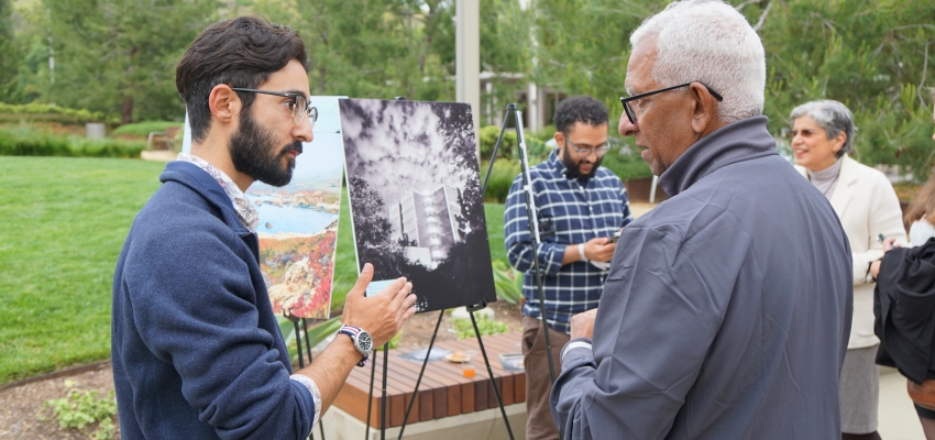 Clifford Danza and Chalat Rajaram, MD, converse about Danza's photo in the background of this outdoor symposium.