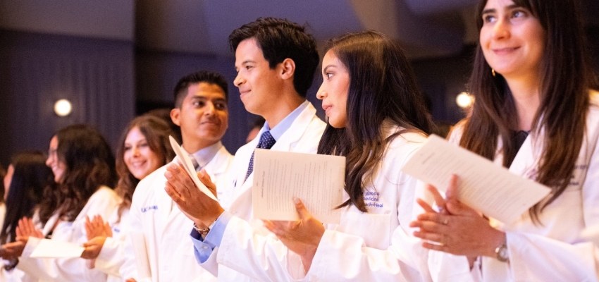 Medical students standing in their white coats to recite an oath. 