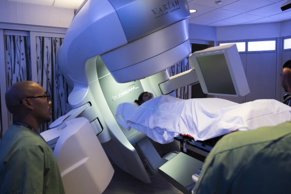 Person under blanket lying on treatment table receiving radiation therapy