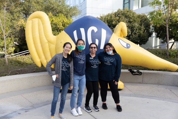 Group photo of 4 people standing in front of a blow up anteater mascot