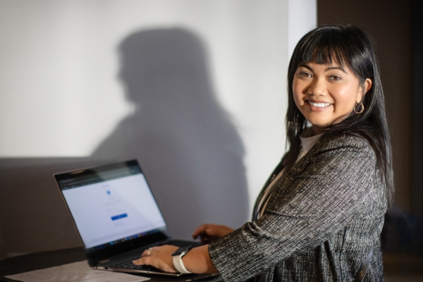 Careesa Garcia, TNT PC-TEAM Manager, smiling towards camera while working on laptop