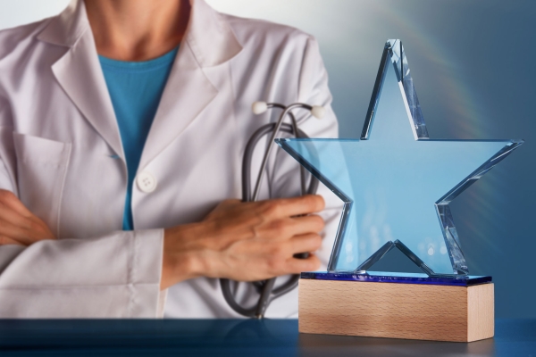 A photo of a physician in behind a glass star award