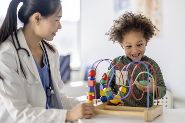 Pediatrician watches toddler play with a game in doctor's office