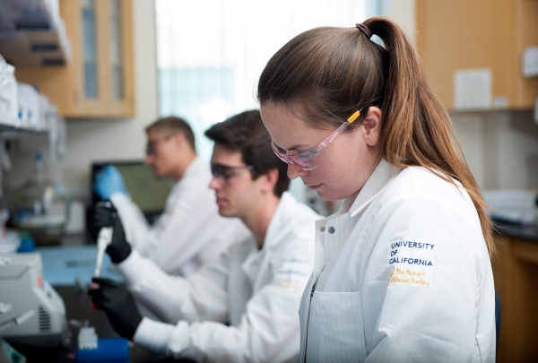 3 researcherss doing microfluidics bench work in biomedical engineering lab.