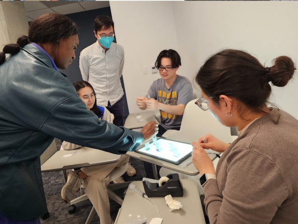 A group of students sit around a four desks working on a technical project as part of the Physician Innovator Training Program
