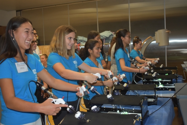 Group of students wearing blue program shirts learning a medical technique.