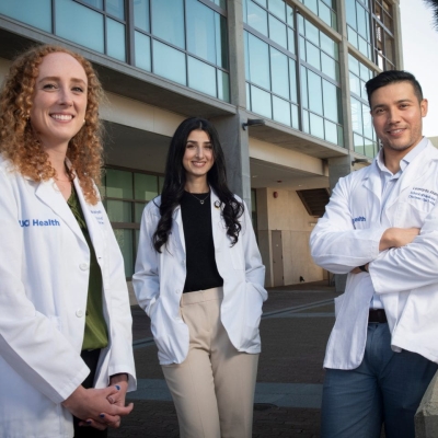 Three students pose together in their white coats. 