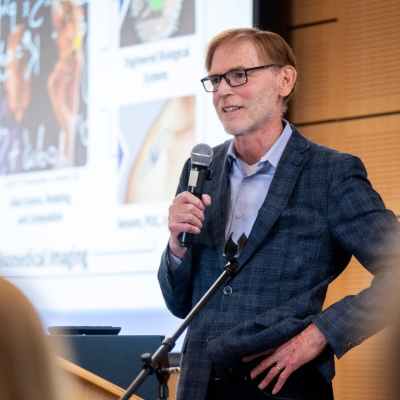 Bruce Tromberg speaking into a microphone at an event. 