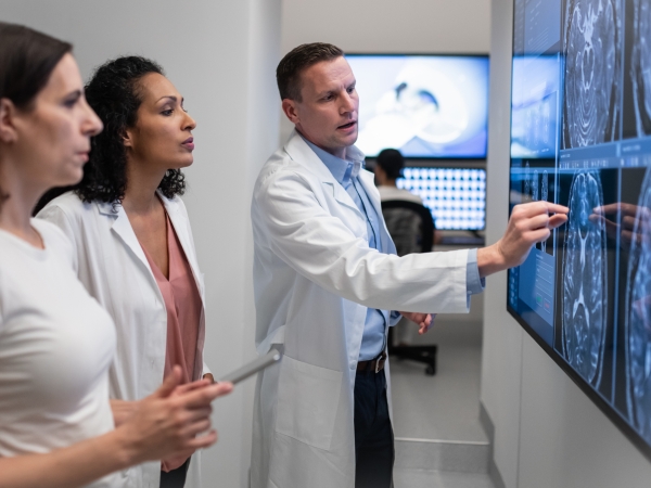 Three doctors review MRI scans and consult.