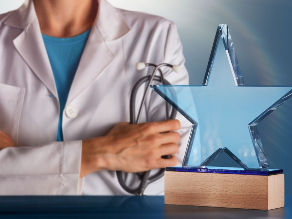 A photo of a physician in behind a glass star award