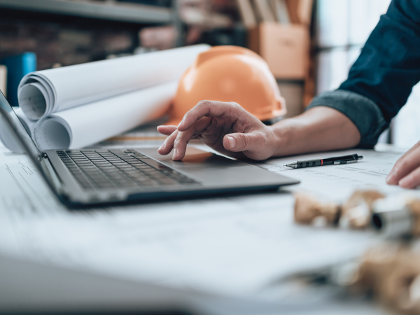 Engineering working with drawings inspection on laptop in the office and Calculator, triangle ruler, safety glasses, compass, vernier caliper on Blueprint. Engineer, Architect, Industry and factory concept.