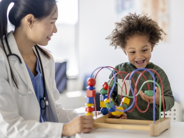 Pediatrician watches toddler play with a game in doctor's office