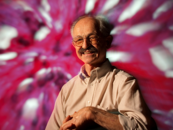 Dan Mercola with a pink and white abstract backdrop