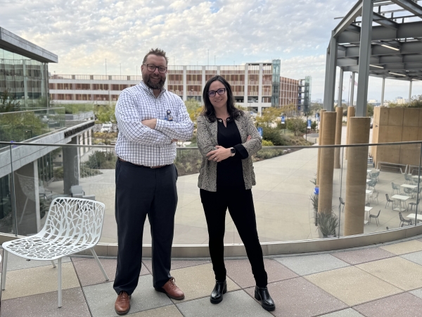 John and Tanya stand next to each other on an outdoor, upstairs patio