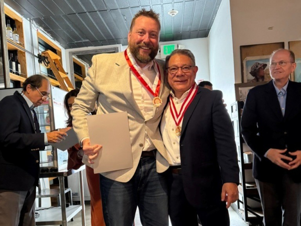 John Billimek and Cesar Aranguri stand together with medals around their necks. Aponte and Casafrancas are in the background.