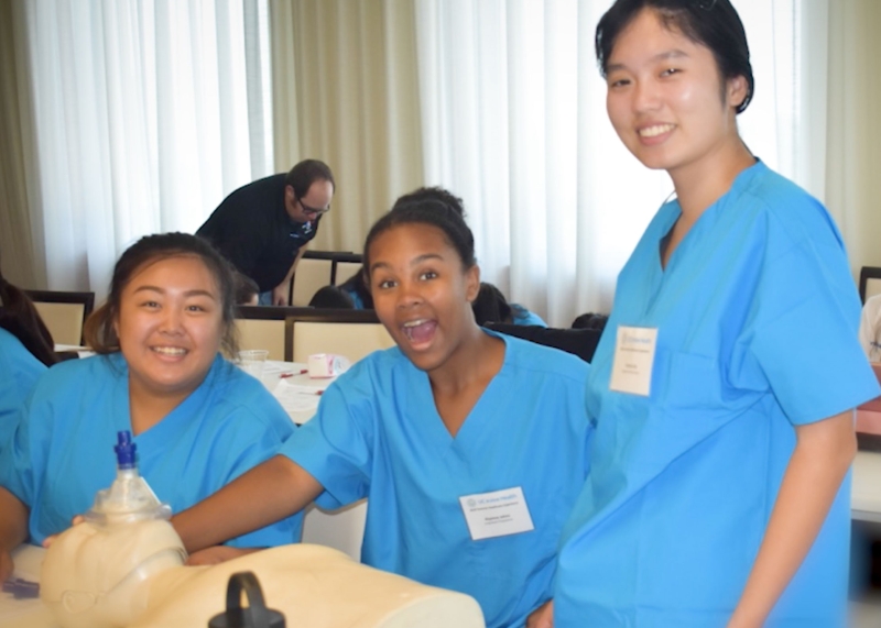 3 SHE Program participants in blue scrubs