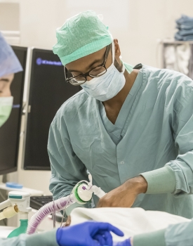 Medical professionals in surgical attire performing a procedure in an operating room.