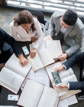 Group of people working at the office doing some research on books and online