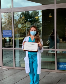 A recent medical graduate proudly holding her diploma.