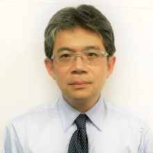 A profile headshot of Katsuhiko Shirahige in a white shirt and black tie