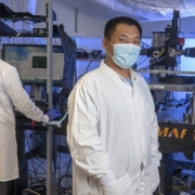 Xiangmin Xu stands in his lab while another person is working on a computer.