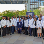 Group photo of 26 people standing together on an outdoor patio.