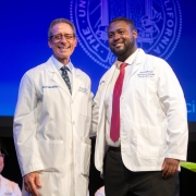 Dean Michael Stamos and Darrys Reece stand on stage at White Coat Ceremony.