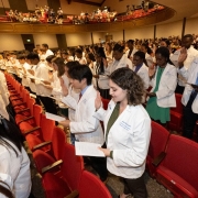 Rows of students at white coat ceremony in their white coats while reciting the Hippocratic oath.