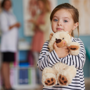 a little girl holding a plush teddy bear