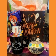 A decorated pumpkin, a Happy Halloween gift bag, and a mug filled with goodies.