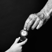 A photo of a child's hand and an adult hand holding a pocket watch