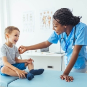 doctors office-female pediatric doctor reaching out to child with both smiling