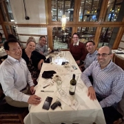 Six people sitting at a dinner table smiling for the camera.