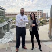 John and Tanya stand next to each other on an outdoor, upstairs patio