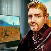 A computer rendering of a young man transitions into a digital avatar beside a computer displaying a virtual landscape.