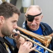 Trombonist playing next to a stroke patient wearing an eye patch. 