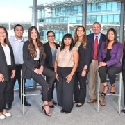 A team of nine people stand together inside UCI building. 