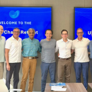 Group photo of seven men standing together in front of a screen that says “Welcome to the UC5 Chairs Retreat”