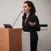Zhina Sadeghi stands behind a podium, speaking