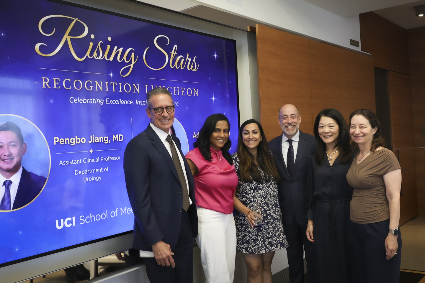 Four women and two men stand together, with Sharma holding her award