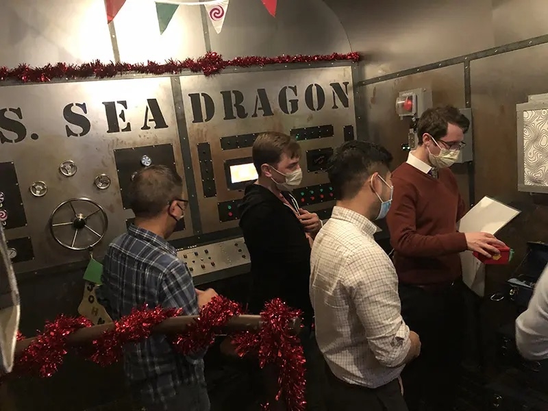 Four masked people at an escape room. On the wall, it says S. Sea Dragon. 