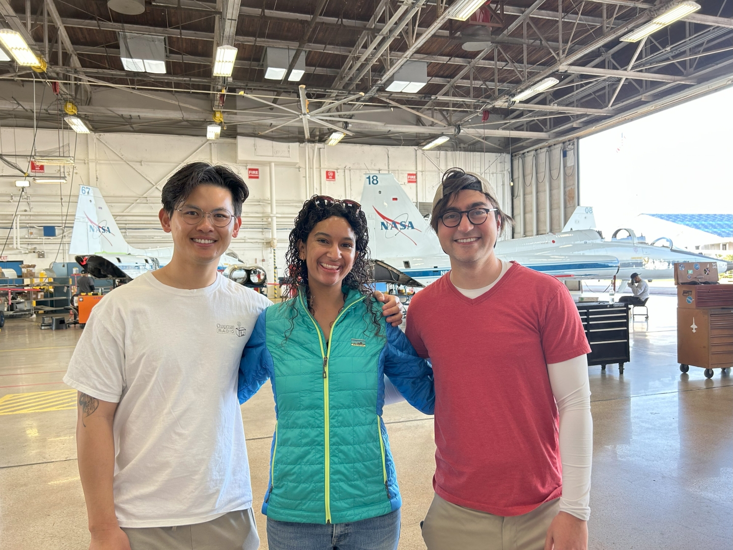 Yang, Curlin, and Sahin stand in a hangar with a NASA jet behind them.