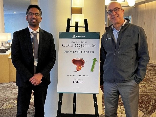 David Benjamin and Arash Rezazadeh Kalebasty standing by a sign that says, “Colloquium on Prostate Cancer.”
