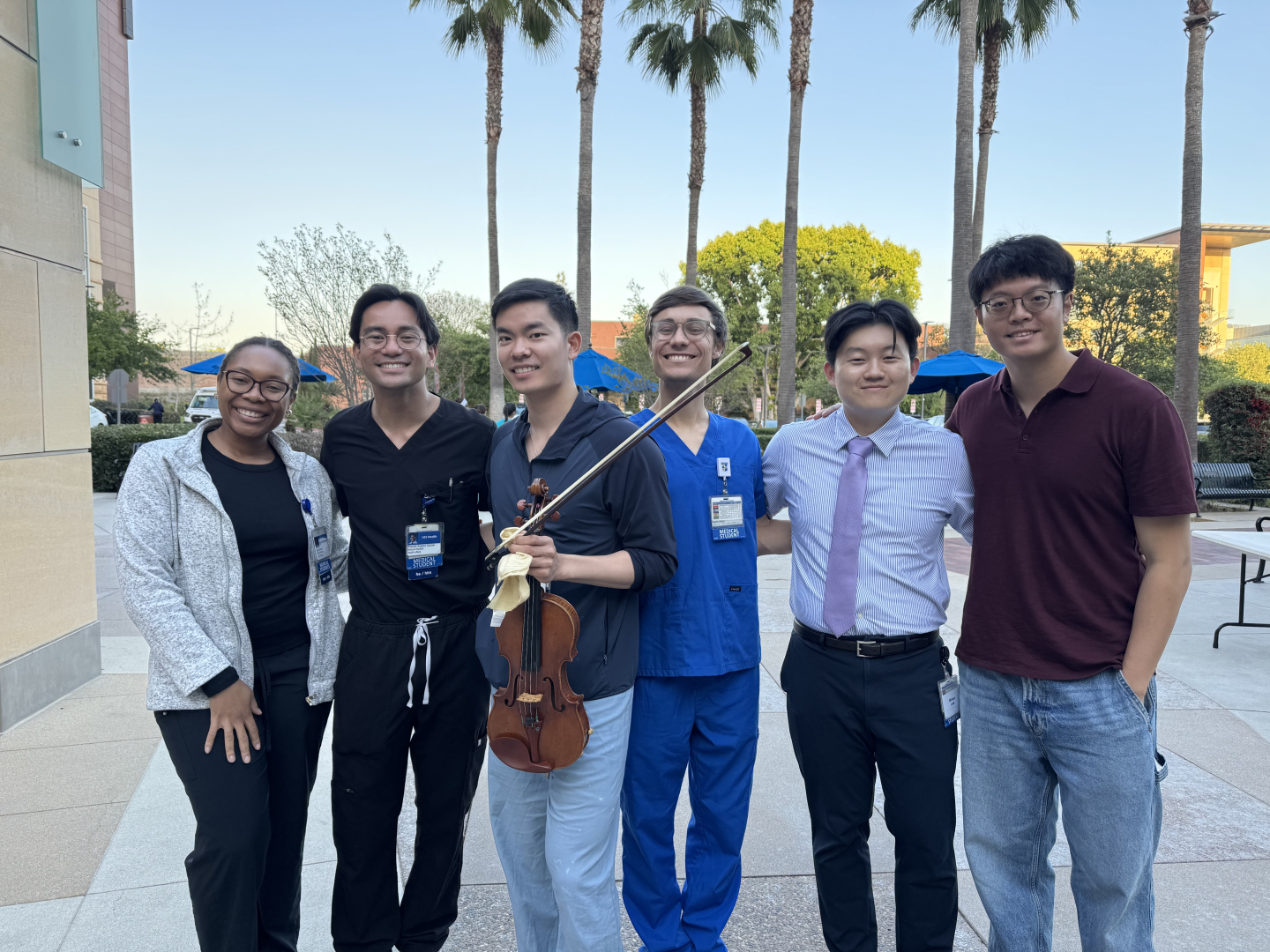 Lee holds his violin as he stands outside with five other students
