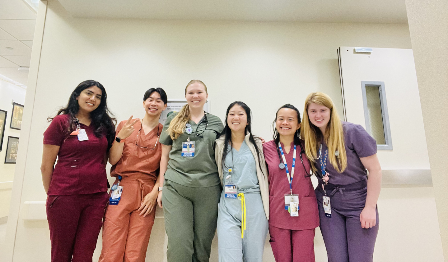 Six people standing together, each wearing brightly colored scrubs.