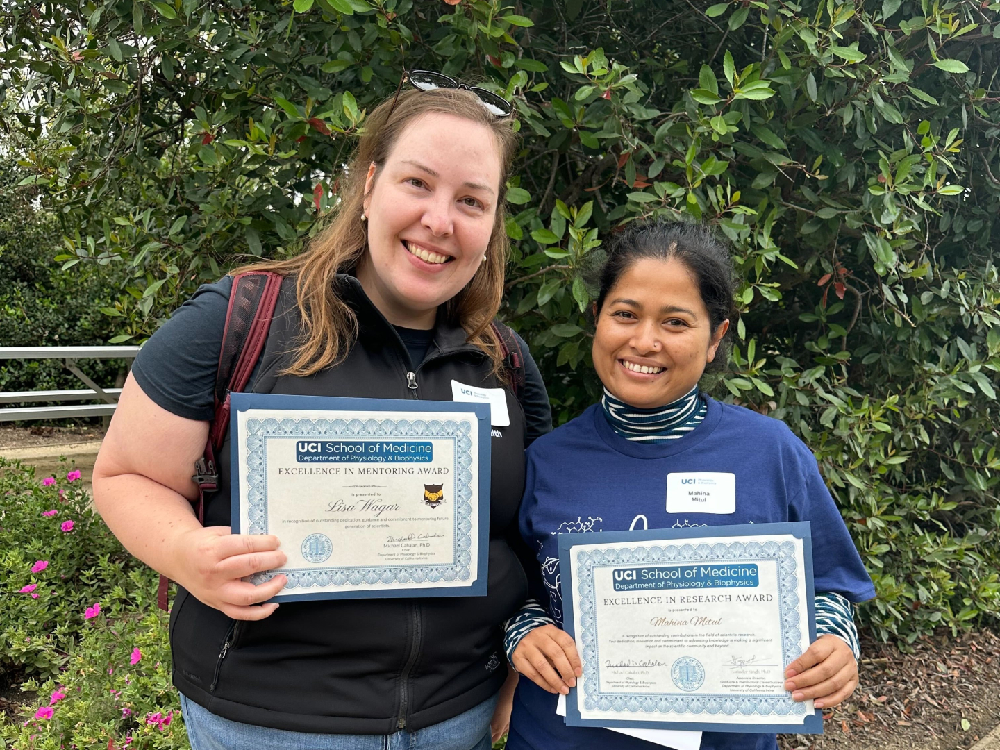 Wagar and Mitul standing outside, holding award certificates