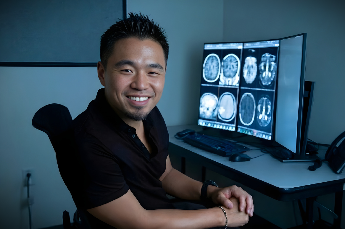 Chang sitting in front of a computer screen showing brain images