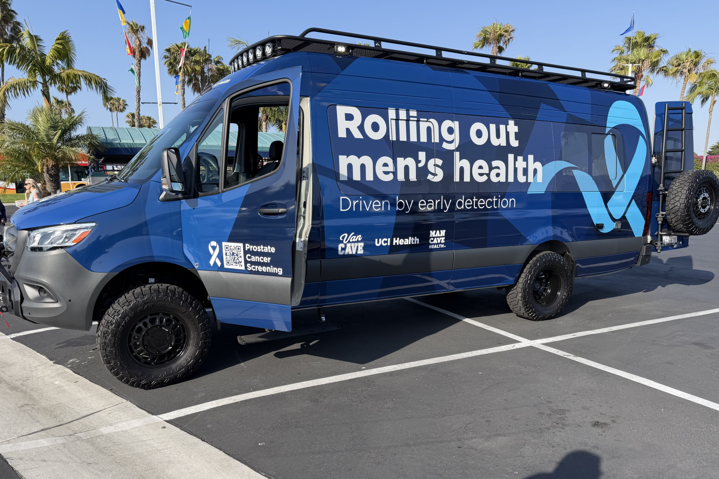 Photo of a large van that says on the side “Rolling out men’s health. Driven by early detection.” The driver’s door says “Prostate Cancer Screening.”