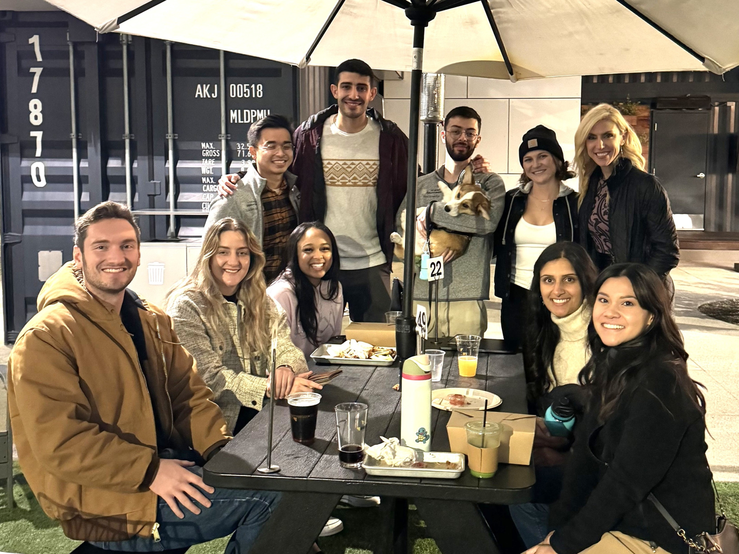 Nine students gathered around a table together (one holding a dog) with Dr. Osborne